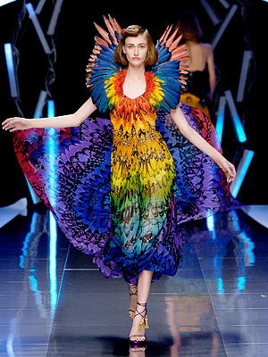 A model walks in a rainbow feathered dress in McQueen's Spring/Summer 2003 show.