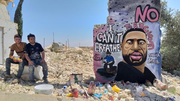 Black Lives Matter everywhere - Syrian painters Aziz Asmar and Anis Hamdoun sit next to a graffiti of George Floyd in Idlib, Syria.
