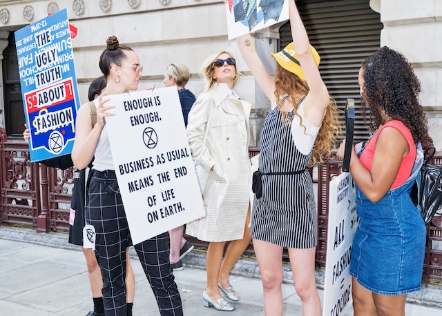 A fashion week-goer walks through protestors at London Fashion Week.