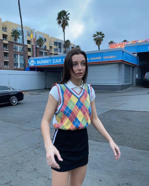 Internet favorite Emma Chamberlain pairs a colorful sweater vest with a fashionably cut skirt.