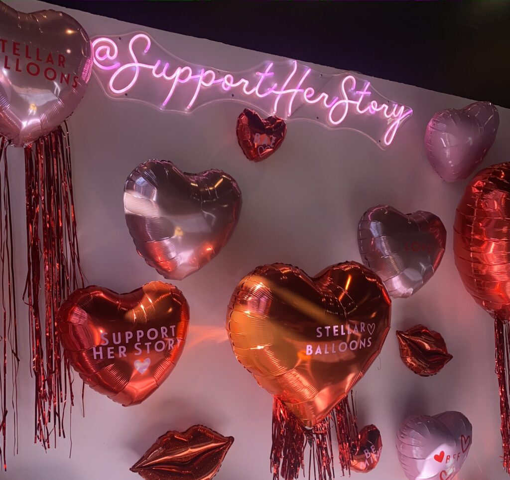 Balloon mural by Stellar Balloons as well as the neon sign showcasing the Support Her Story Instagram